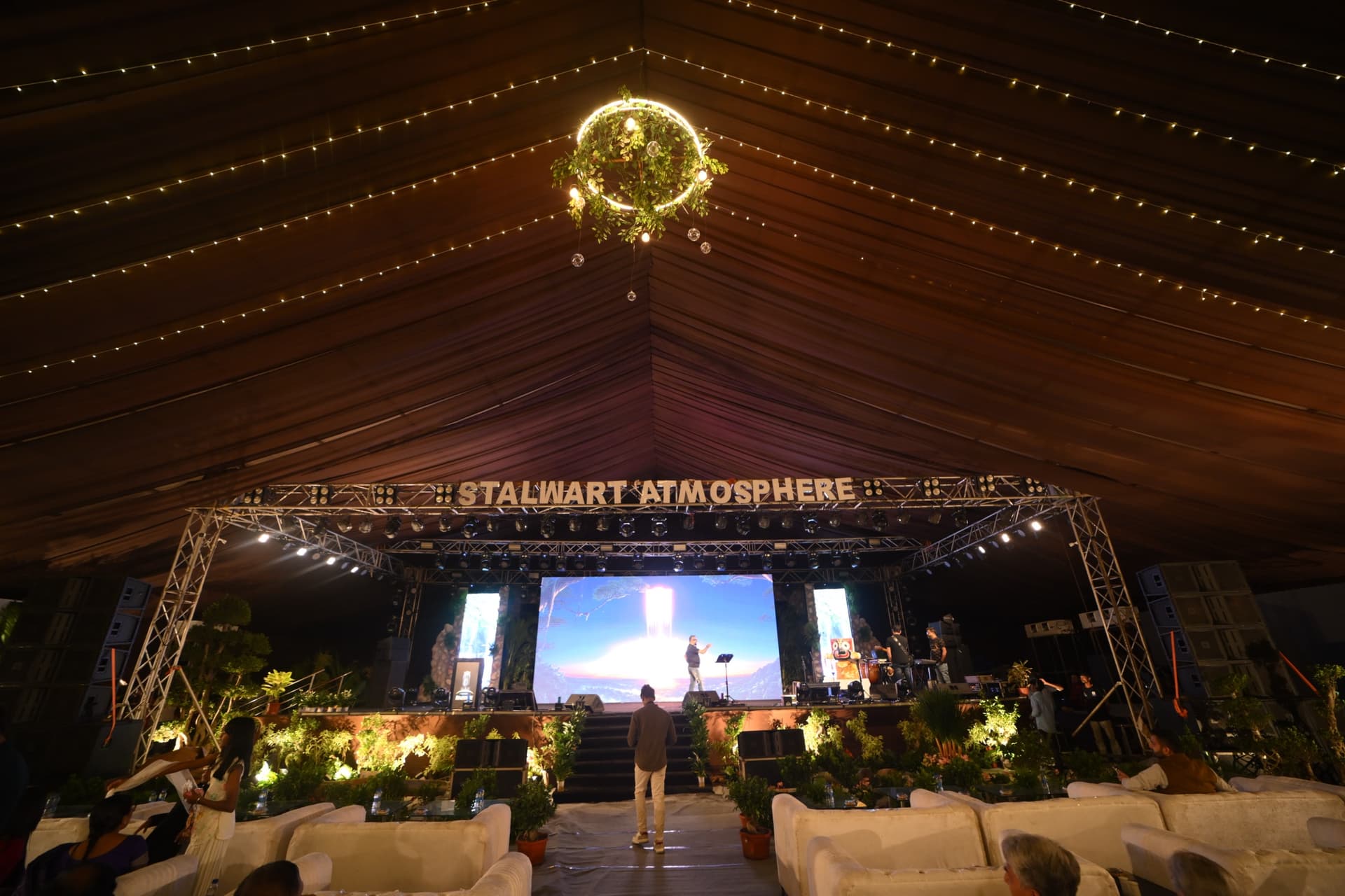 Large-scale event stage with screen and lounge seating for guests