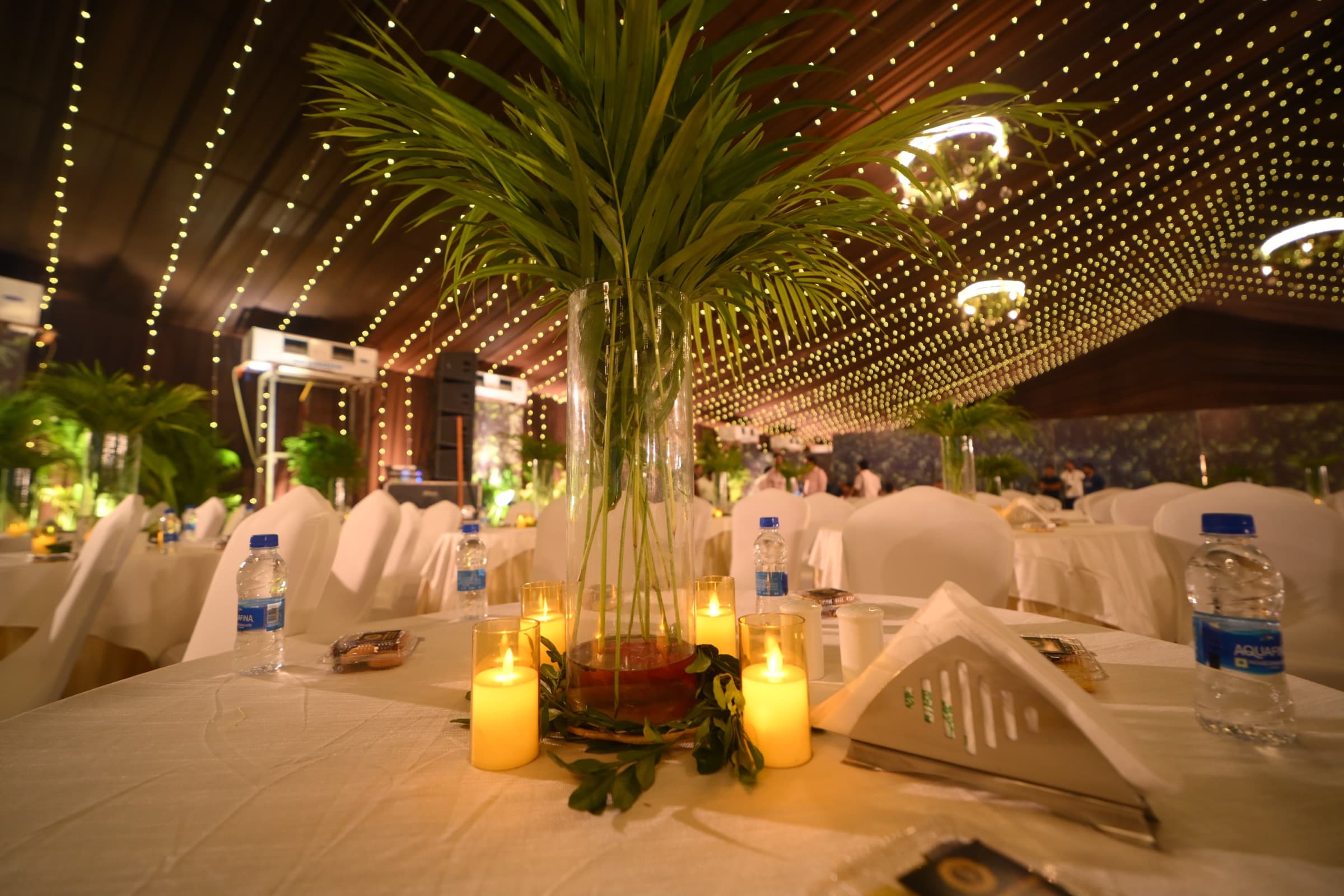 Candlelit reception table centerpiece with palm leaves at a launch event